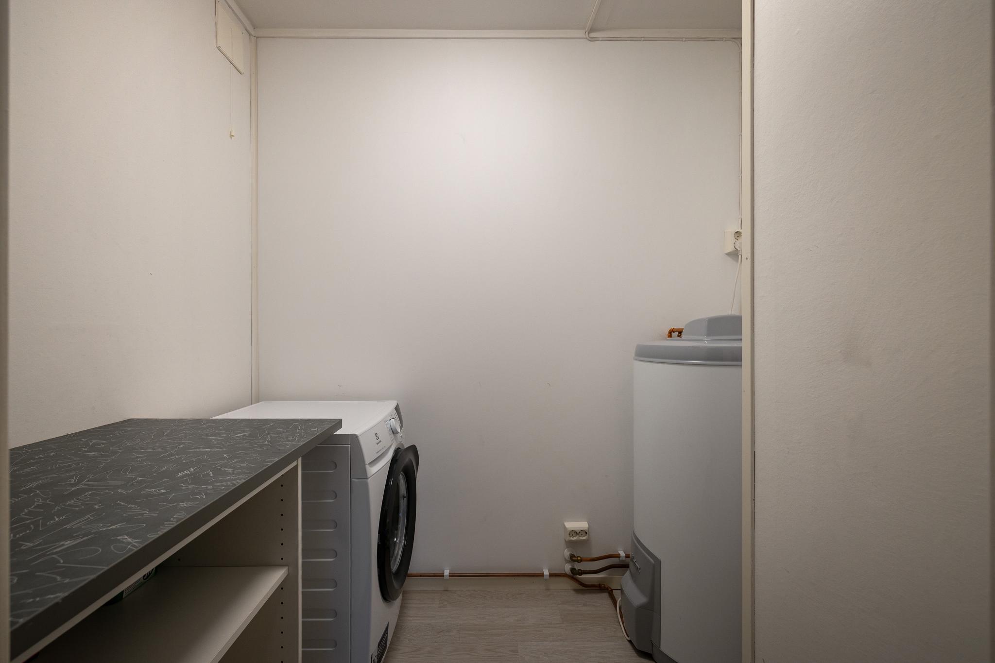 Vaskerom med vaskemaskin, tørkestativ og støvsuger.